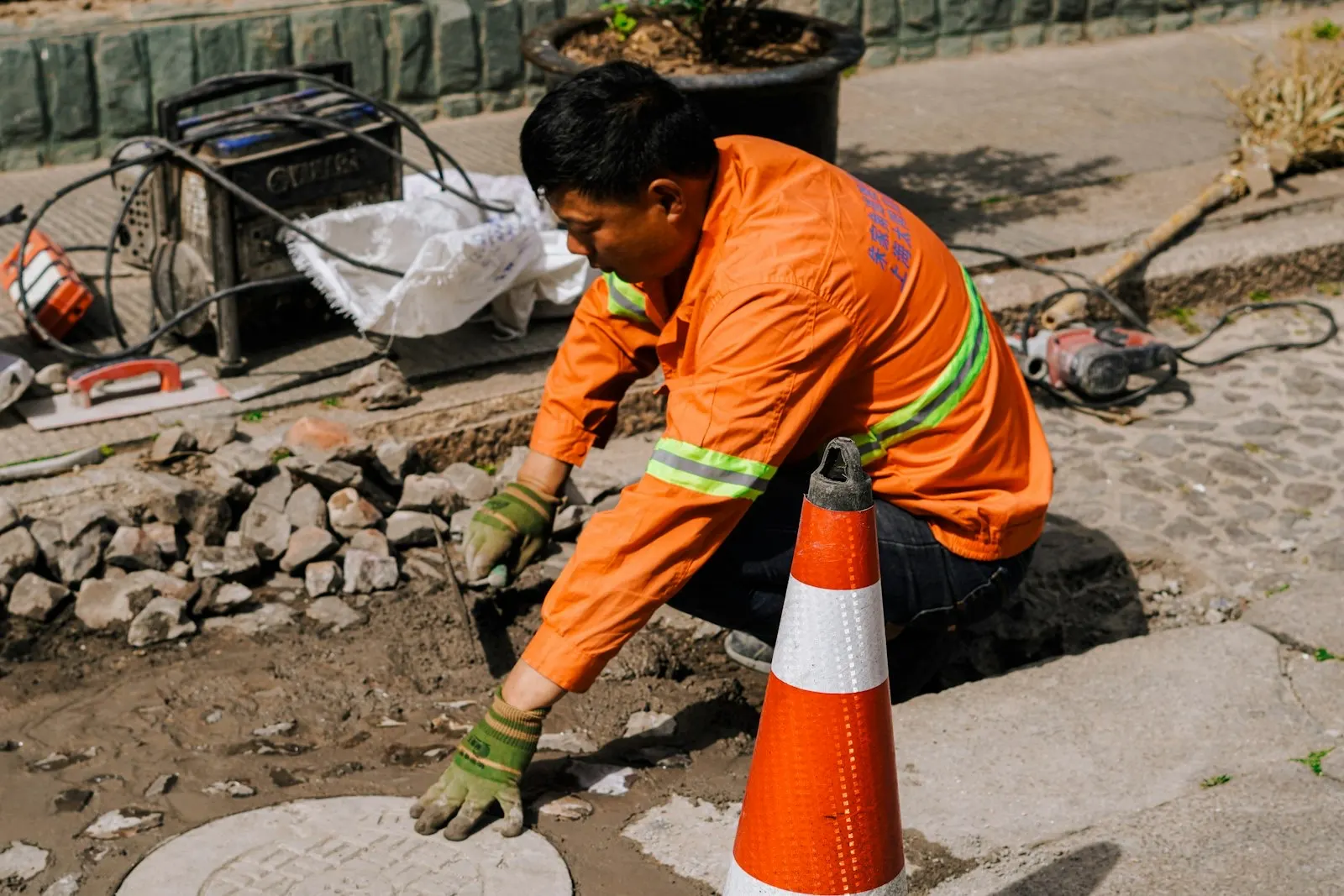 Drainage worker inspecting an open manhole